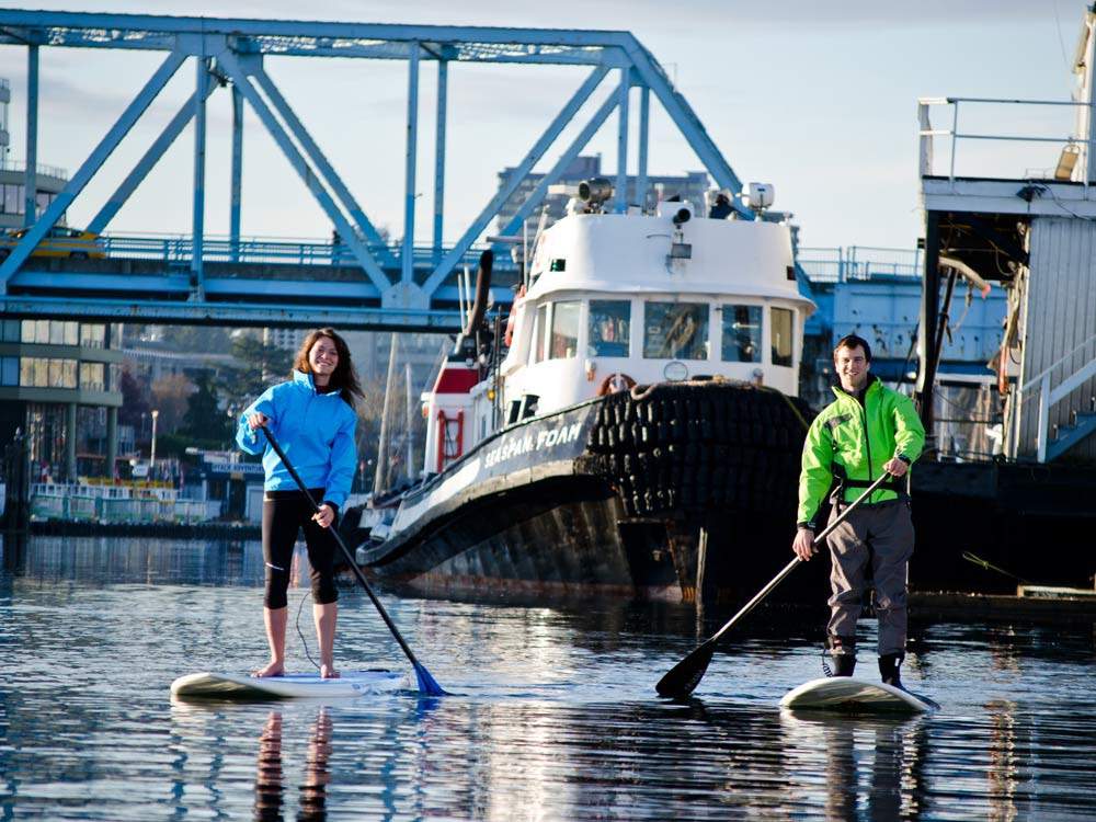 Paddle boarders cruise under Victoria's Johnson Street Bridge.