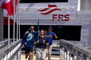 Seattle Mariners fans walk down the Victoria Clipper gangway with team flags in front of the FRS Clipper ferry.